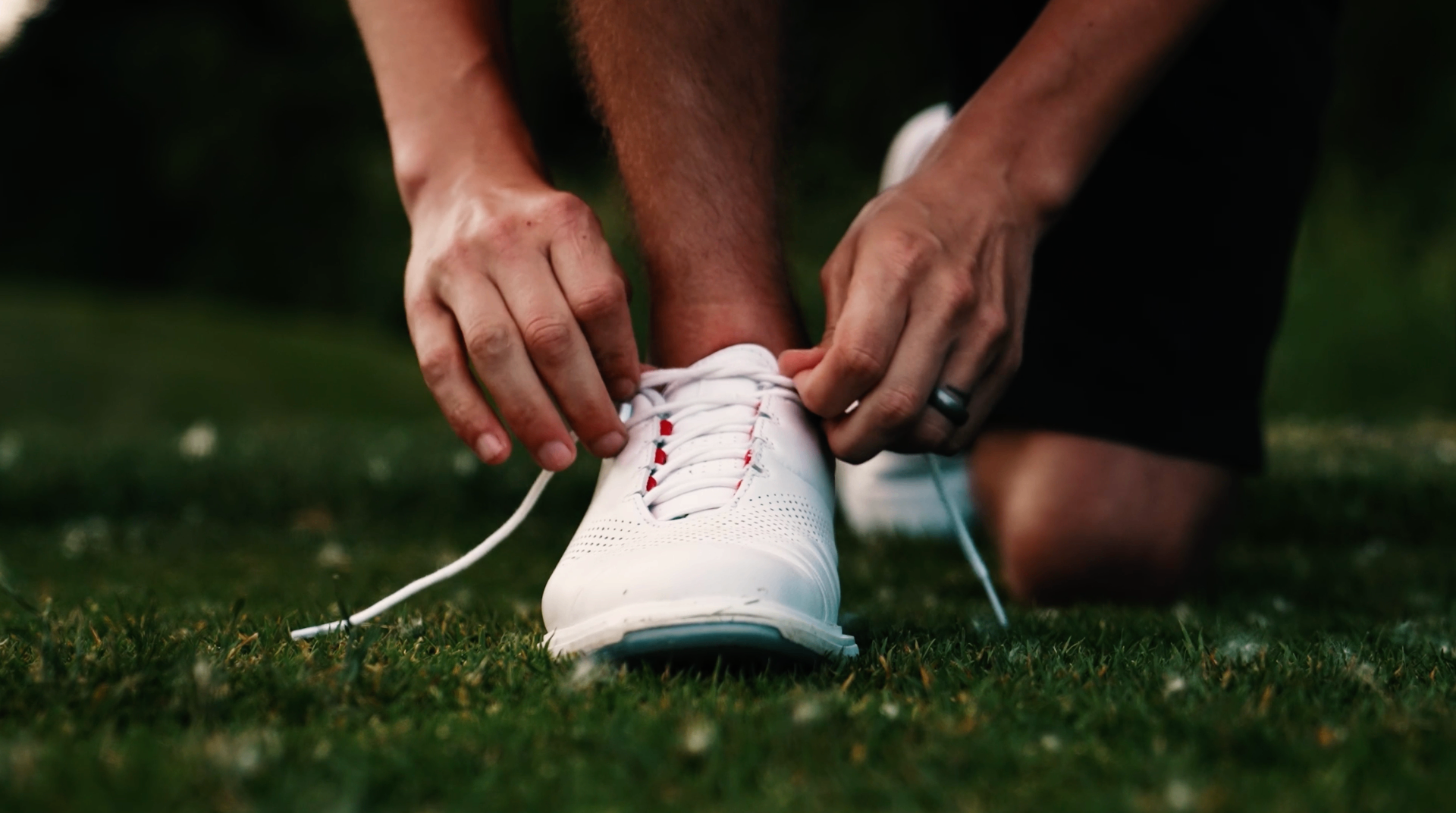 Close-up of golf shoes being laced on the green
